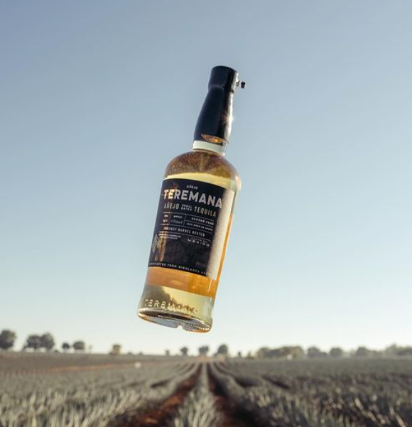 Tequila Teremana Añejo w otoczeniu eleganckich kieliszków i dębowych beczek, symbolizująca najwyższą jakość i dbałość o szczegóły w produkcji